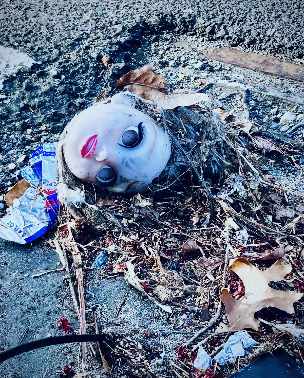 Discarded doll head and debris resting on a steel grate.