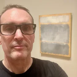 Close selfie of Thad with the Rothko painting Grays in Yellow visible behind him.