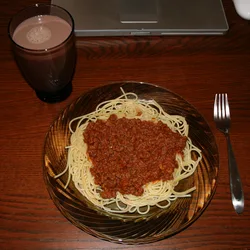 Plate of spaghetti with meat sauce next to a glass of chocolate milk