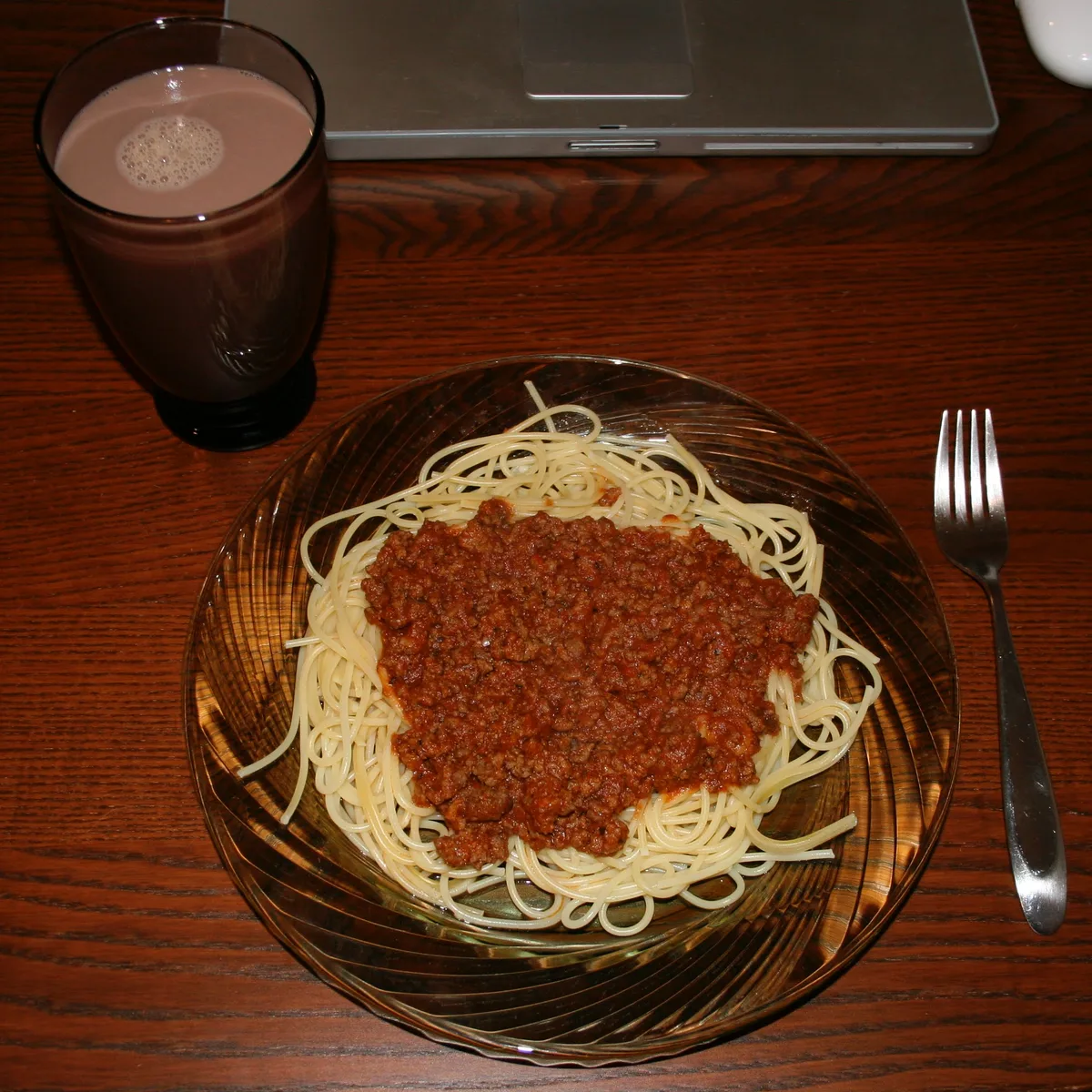 Plate of spaghetti with meat sauce next to a glass of chocolate milk