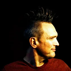 Profile portrait of Thad with a dark mohawk lit from the side