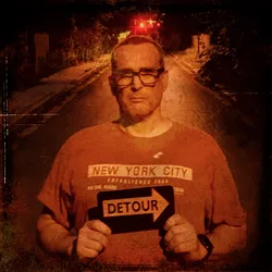 Portrait of me standing on a dimly lit road at night, holding a 'DETOUR' sign with an arrow pointing right. The image has a distressed, textured effect and red traffic lights glow in the background.