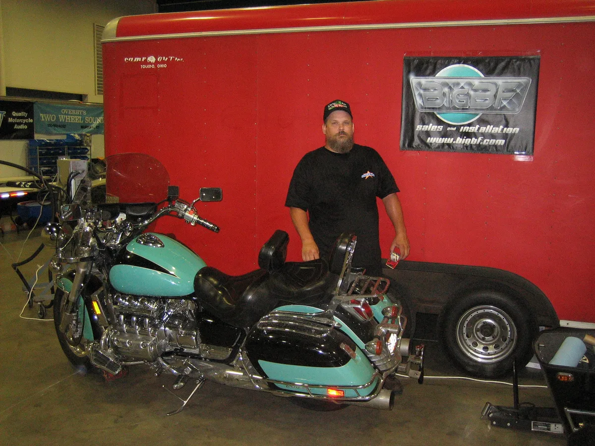 Bill standing next to his motorcycle with the sign mounted on the trailer behind him