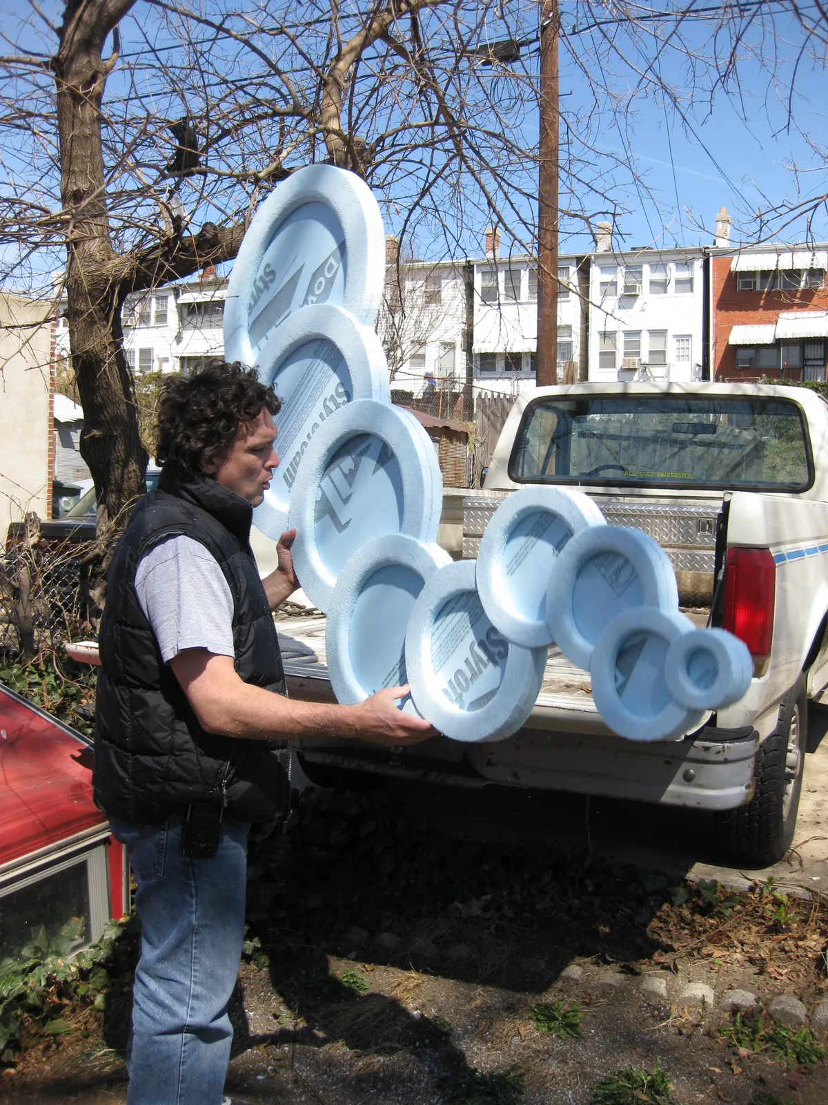 Thad standing outdoors gluing the foam circle assembly for Dried Up before bringing it inside to paint.