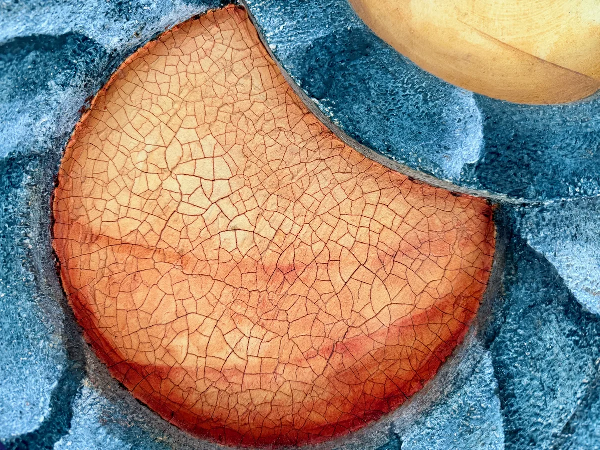 Detail shot of a heavily cracked, sun-dried textured surface in orange and rust tones.