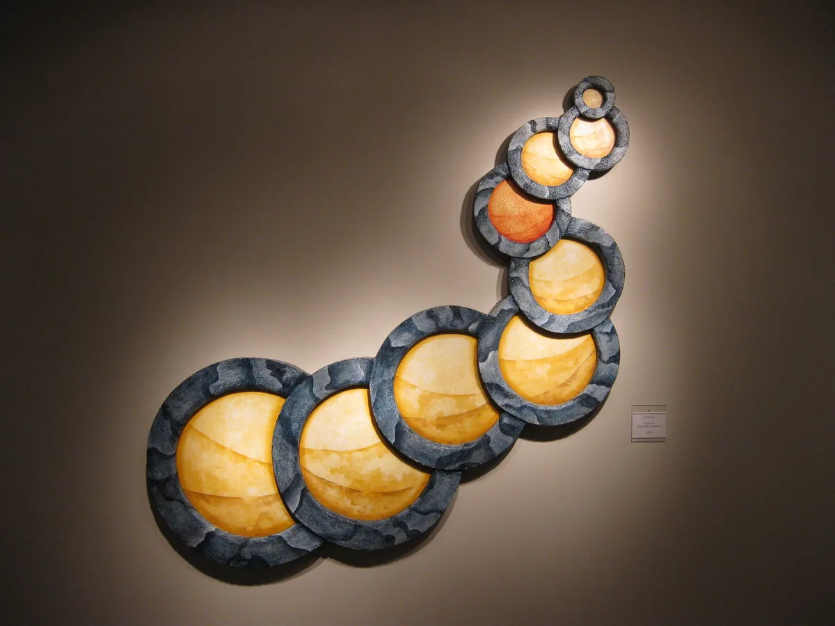 Dried Up displayed and lit in the gallery, wall placard visible beside it.