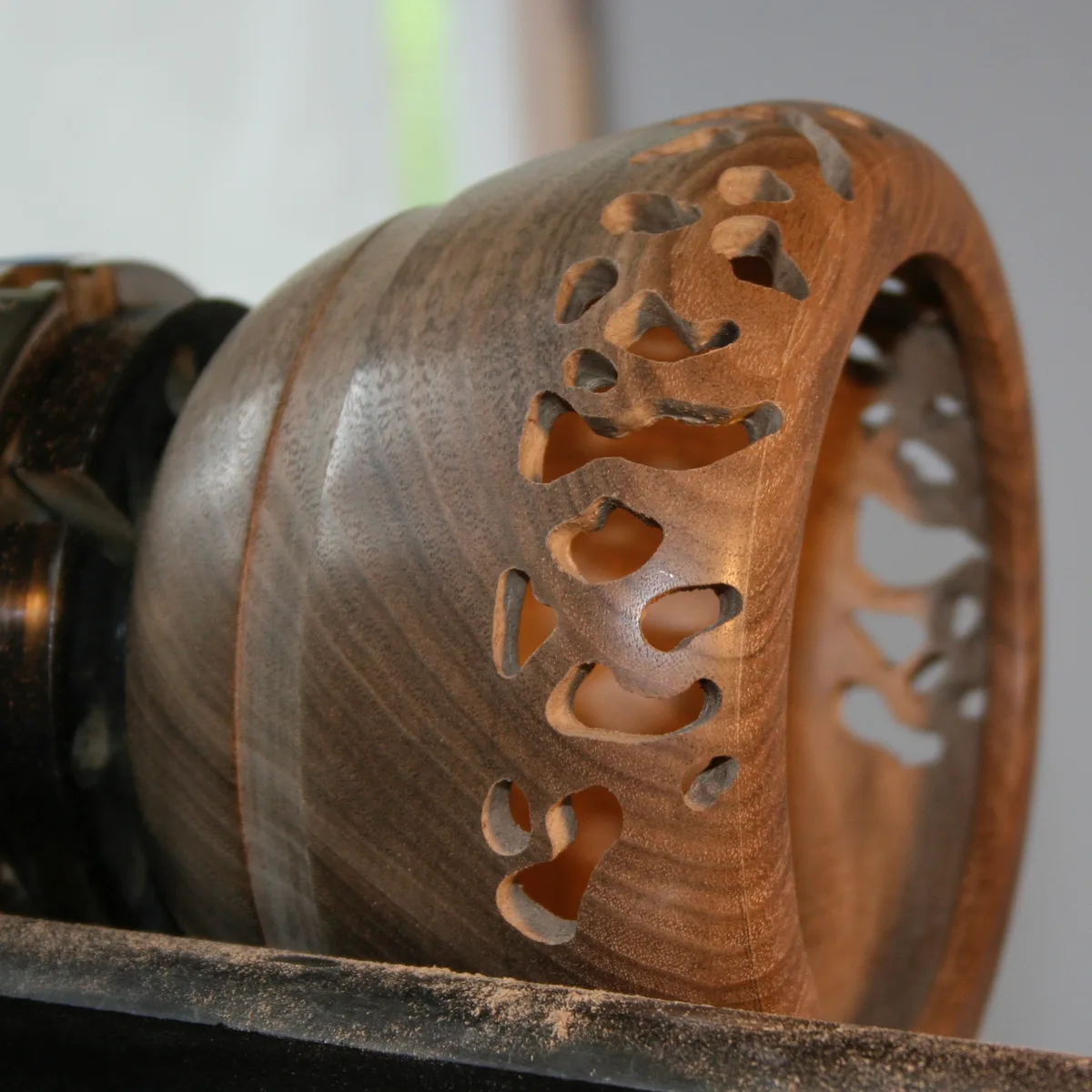 Walnut bowl on the lathe with openwork holes drilled about halfway through