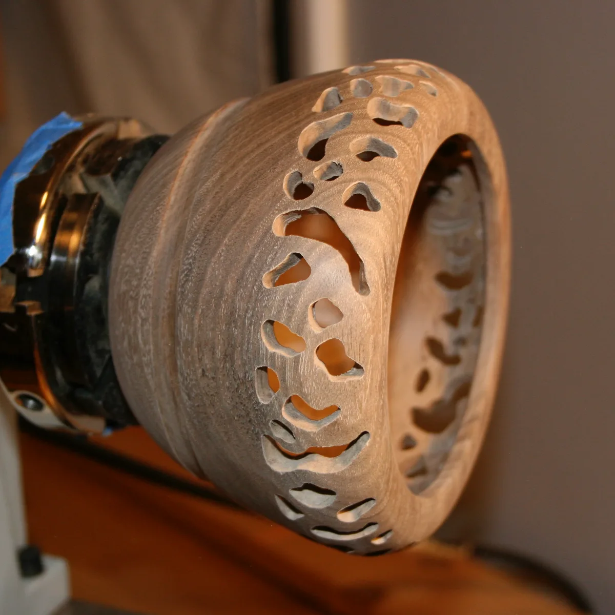 Walnut bowl on the lathe with the openwork pattern completed