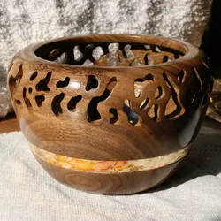 Wooden turned bowl with drilled lace-like hole pattern and a flake inlay band