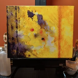 Abstract painting on an easel in yellow orange with purple accents