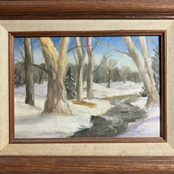 Framed oil painting of a snowy forest with a stream running through it
