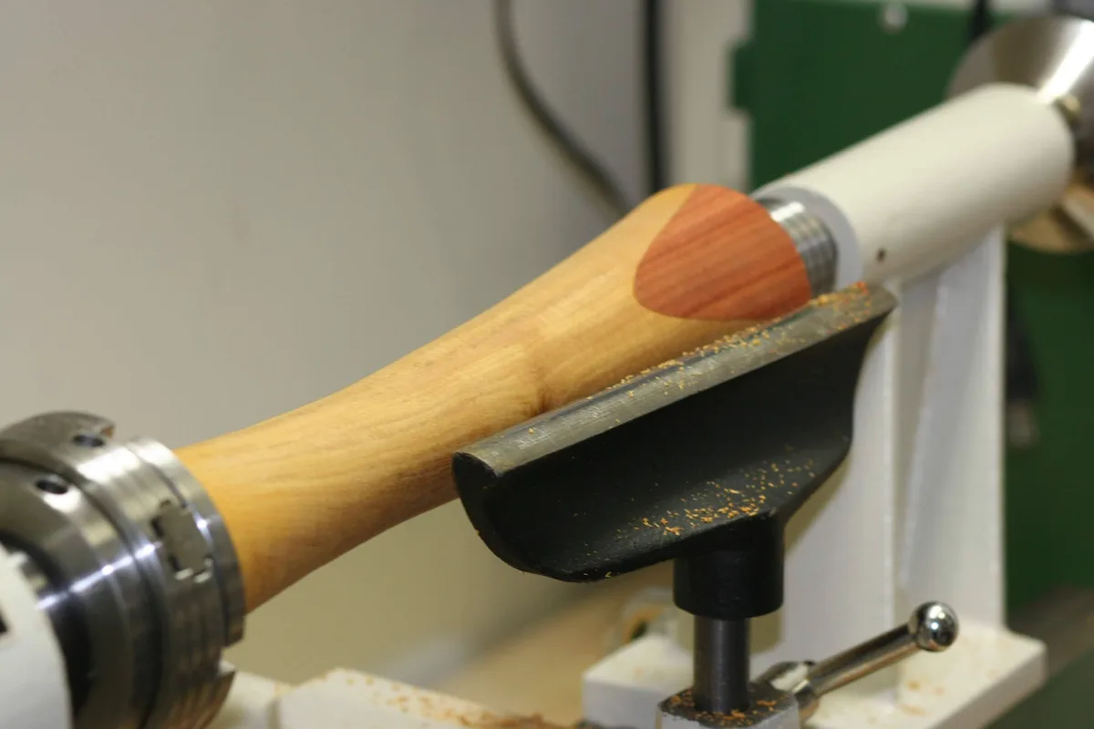 Wood column on the lathe with the tool rest positioned near the patch