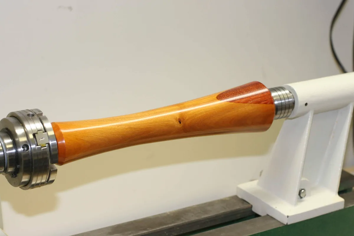Finished and polished wood spindle showing the waisted shape and wood patch
