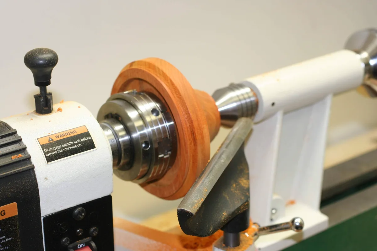 Wide wood blank mounted on the lathe chuck with the tool rest in place